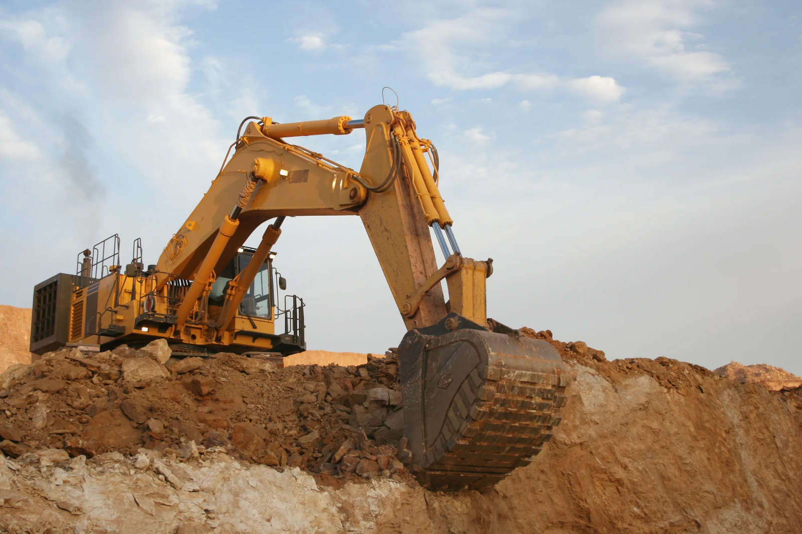 Excavator digs into a dirt shelf.