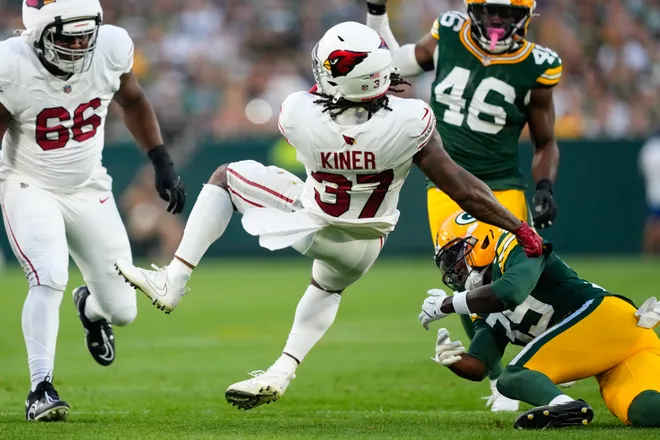 Aug 28, 2026; Green Bay, Wisconsin, USA;  Arizona Cardinals running back Corey Kiner (37) is tackled with the football during the first quarter against the Green Bay Packers at Lambeau Field. Mandatory Credit: Jeff Hanisch-Imagn Images