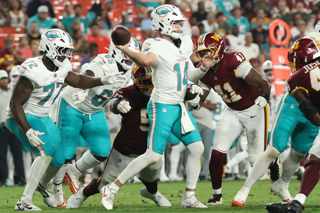 Aug 14, 2026; Landover, Maryland, USA; Miami Dolphins quarterback Quinn Ewers (14) passes the ball before being hit by Washington Commanders defensive tackle Ricky Barber (50) and Commanders linebacker Javontae Jean-Baptiste (41) during the first half at Northwest Stadium. Mandatory Credit: Geoff Burke-Imagn Images