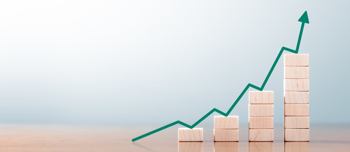 Upward green arrow over bar chart made of blocks.