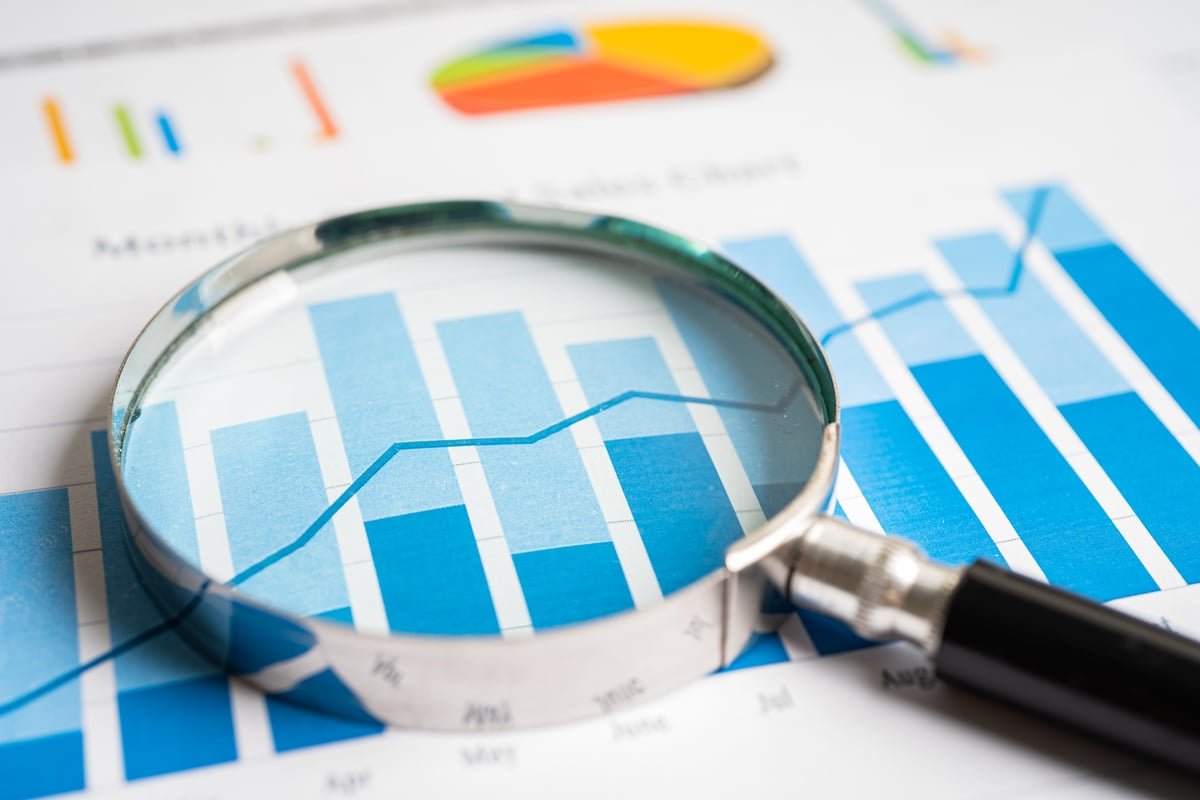 A magnifying glass looking at chart lines.