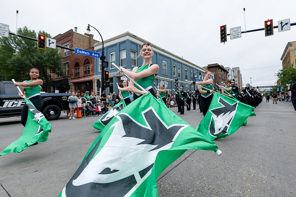 UND color guard members perform with large green Fighting Hawks flags at the intersection of DeMers Avenue during the Potato Bowl Parade.