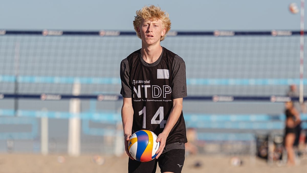 A boys beach volleyball player gets ready to serve