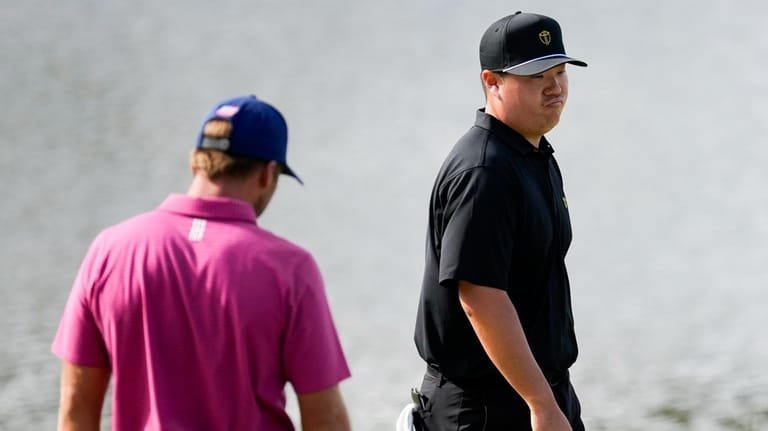 USA teams' Sam Burns, left, looks on as International teams'...