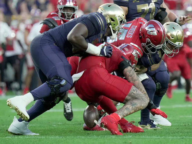 Wisconsin linebacker Sebastian Cheeks (15) forces a fumble by Notre Dame quarterback CJ Carr (13) during the first quarter of their game Sunday, September 6, 2026 at Lambeau Field in Green Bay, Wisconsin. Notre Dame recovered the ball.