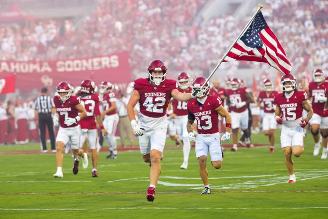 Sep 19, 2026; Norman, Oklahoma, USA; Oklahoma Sooners defensive lineman Wyatt Gilmore (42) runs onto the field with the American flag before the game against the New Mexico Lobos at Gaylord Family-Oklahoma Memorial Stadium. Mandatory Credit: Kevin Jairaj-Imagn Images