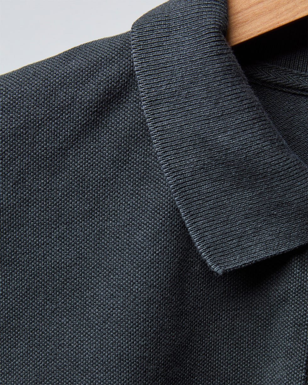 Dark textured polo shirt collar on a wooden hanger. Dark textured polo shirt collar on a wooden hanger.
