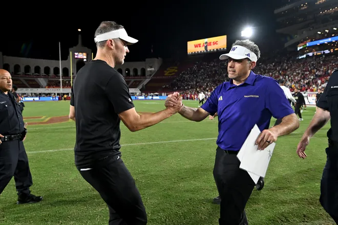 Oct 3, 2026; Los Angeles, California, USA;  USC Trojans head coach Lincoln Riley and Washington Huskies head coach Jedd Fisch shake hands after the game at United Airlines Field at Los Angeles Memorial Coliseum.  Mandatory Credit: Griffin Hooper-Imagn Images